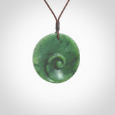 This pendant is a medium sized and cupped koru necklace carved from a lovely piece of New Zealand Jade. Kyohei Noguchi carved this piece for us so the workmanship is outstanding. Handmade in New Zealand, a beautiful piece of jade jewellery. Provided with an adjustable brown cord and packaged in a woven kete pouch.
